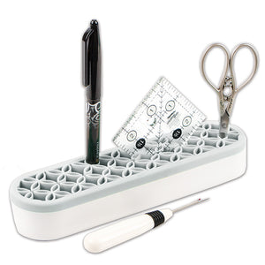 Stash n Store is an elongated oval shape.  It has a white plastic bottom and a gray silicone top with flexible grooves that hold sewing supplies.