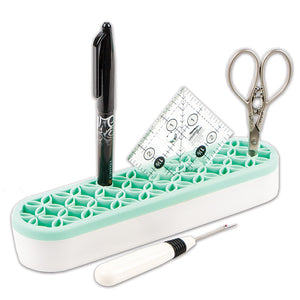 Stash n Store is an elongated oval shape.  It has a white plastic bottom and a mint colored silicone top with flexible grooves that hold sewing supplies.