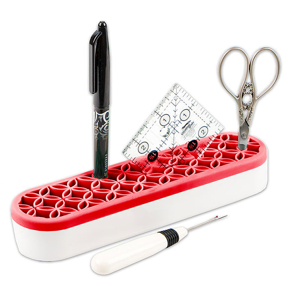 Stash n Store is an elongated oval shape.  It has a white plastic bottom and red silicone top with flexible grooves that hold sewing supplies.